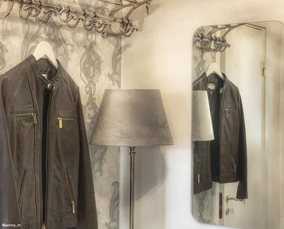 Eteisen sisustus - hattuhylly ja metalliset koukut, suorakulmainen peili ja harmaa valaisin