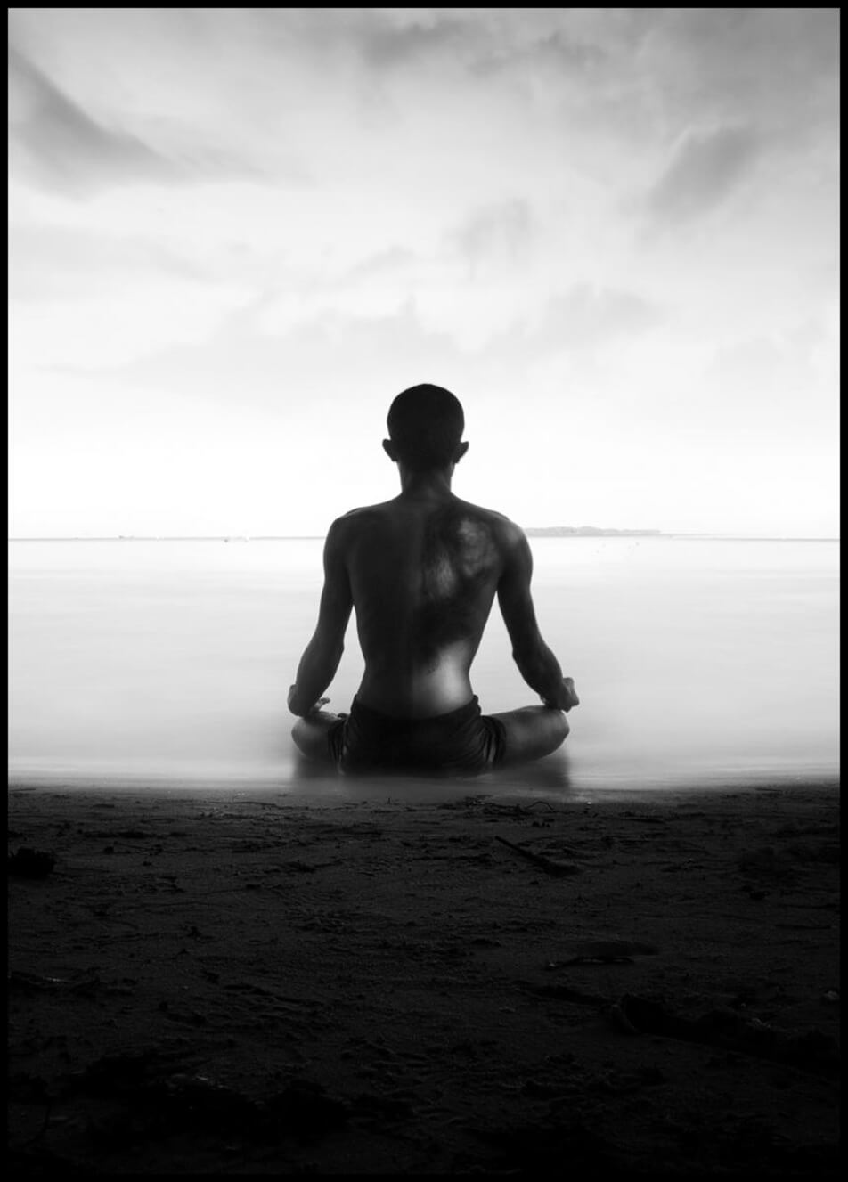 Juliste esittää valokuvaa miehestä, joka meditoi rantaviivan tuntumassa