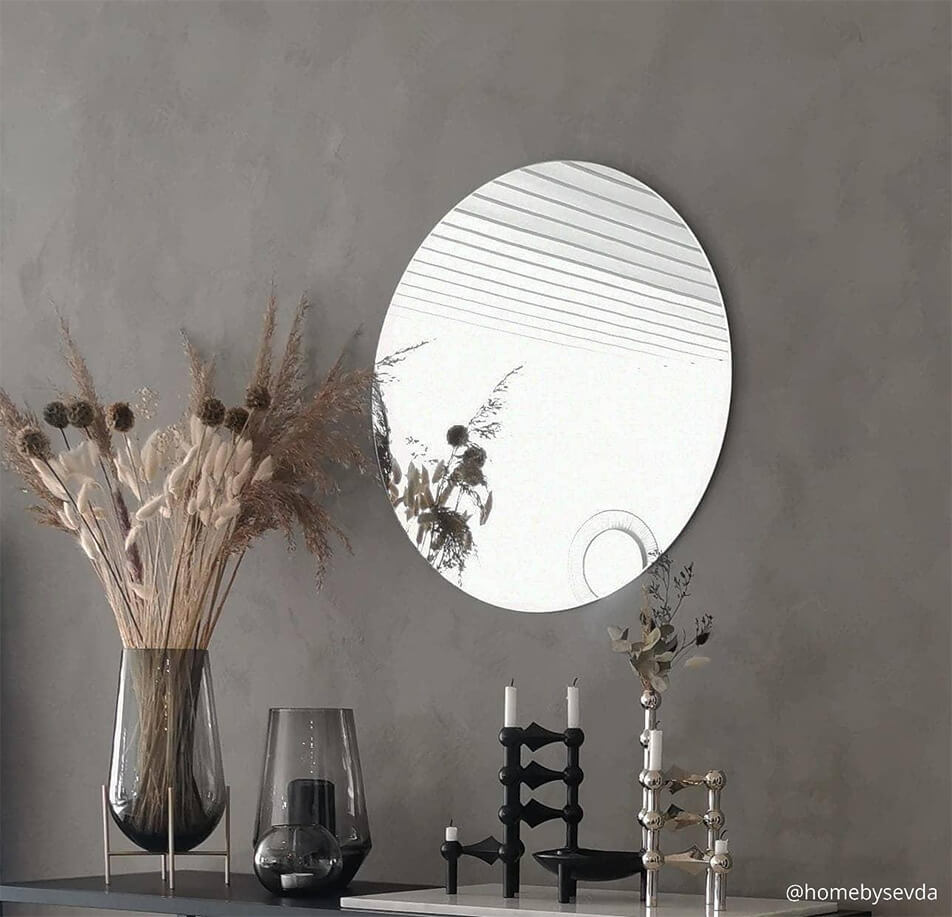 Pyöreä peili harmaalla seinällä